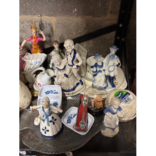 53 - Shelf containing assorted china pieces including figurines, teapots, and decorative wares. Includes ... 