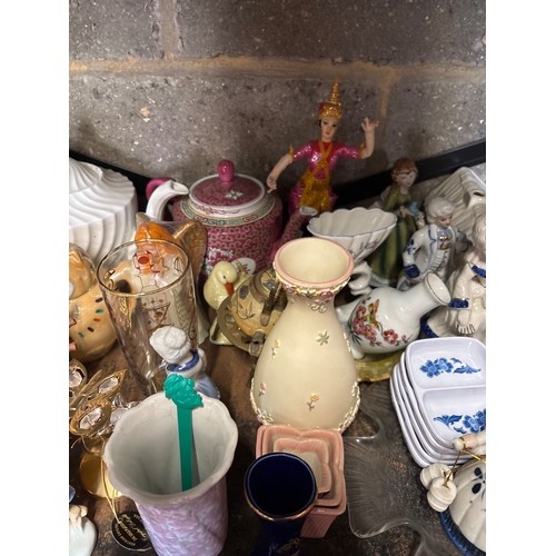 53 - Shelf containing assorted china pieces including figurines, teapots, and decorative wares. Includes ... 