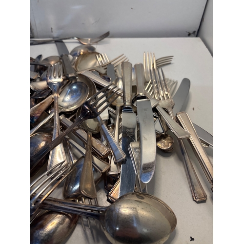25 - Silver-tone flatware includes forks, knives, and spoons. Condition varies, showing signs of use and ... 