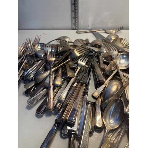 25 - Silver-tone flatware includes forks, knives, and spoons. Condition varies, showing signs of use and ... 
