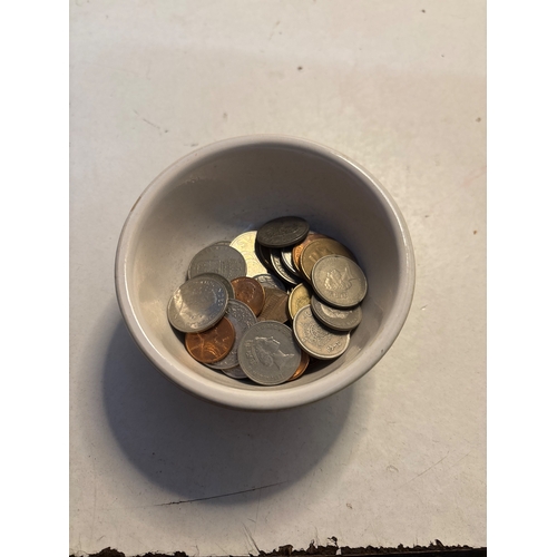 448 - A small white ceramic bowl containing various currency coins.