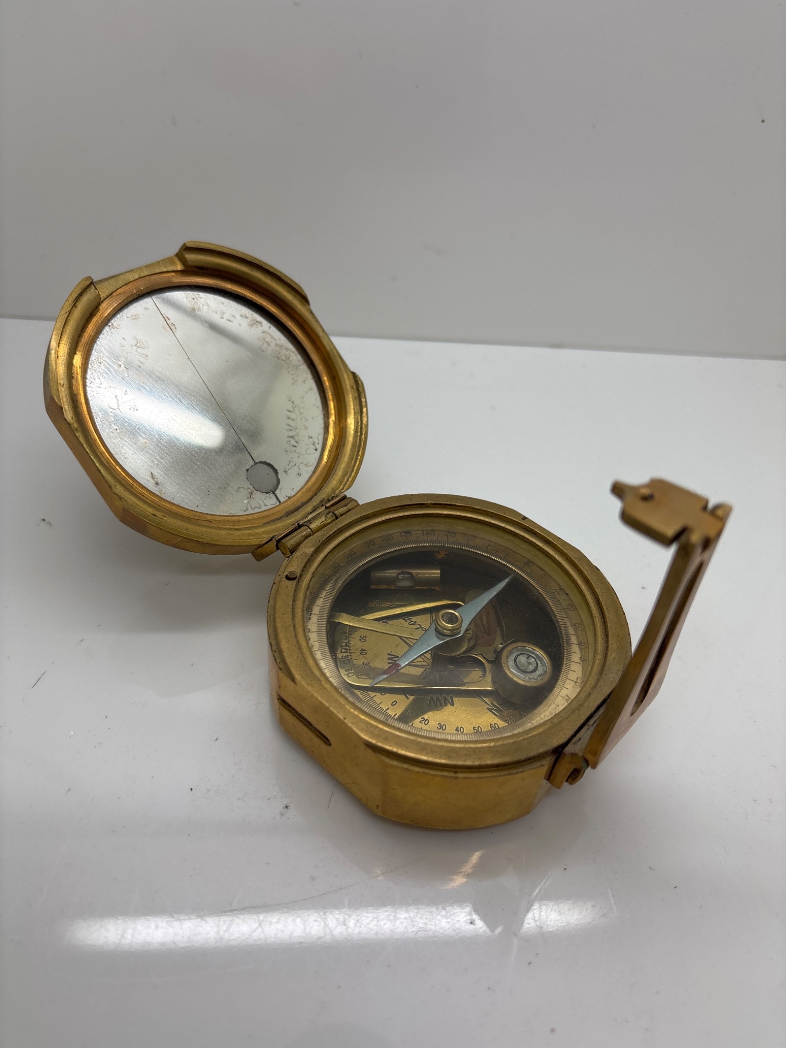 Brass pocket compass with mirrored lid and glass face.