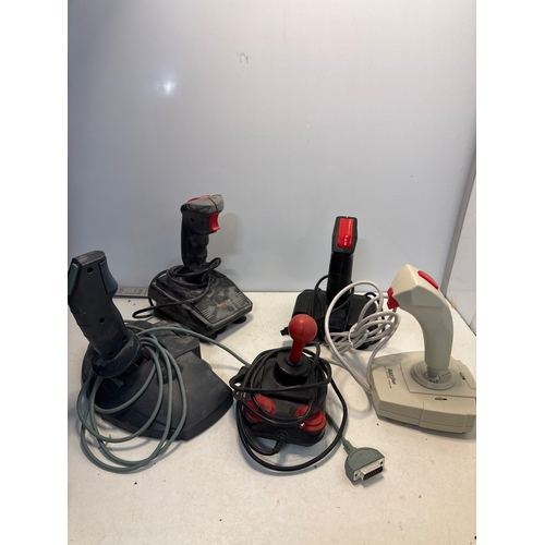 106 - Four vintage joysticks with buttons and cords, various models.