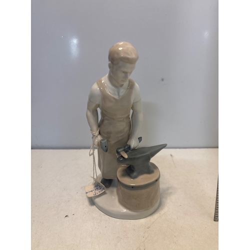 25 - Porcelain figurine of a blacksmith at an anvil, marked '26' and '202' on the base, in good condition... 