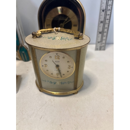 5 - Four assorted table clocks, including ceramic, metal, and stone pieces with decorative elements and ... 