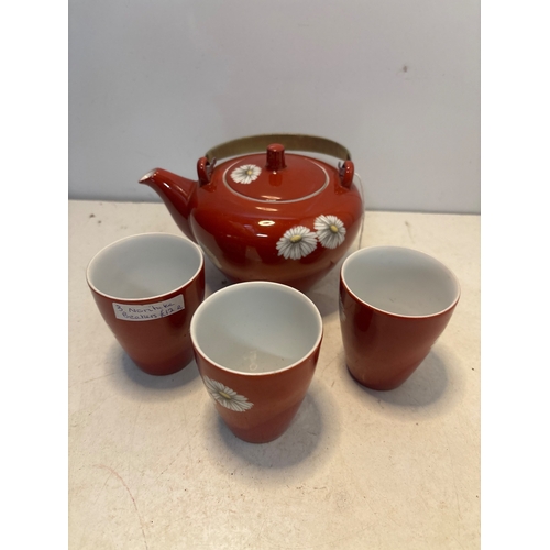 56 - Red ceramic tea set with daisies, includes teapot and three cups not postable.