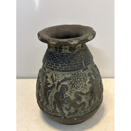 93 - Engraved ceramic vase with detailed warrior motifs. Likely handcrafted. Condition shows wear consist... 