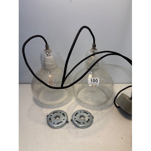 100 - Two clear glass pendant lights with fixtures, black cords, and metal mounting plates. Both lights ar... 