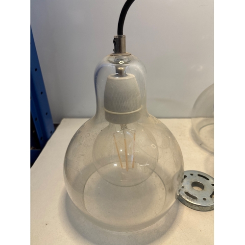 100 - Two clear glass pendant lights with fixtures, black cords, and metal mounting plates. Both lights ar... 