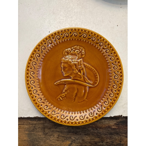 126 - Circular ceramic plate with embossed figure, glazed amber finish
