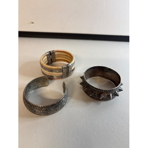 31 - Three metal and mixed-material bangles.