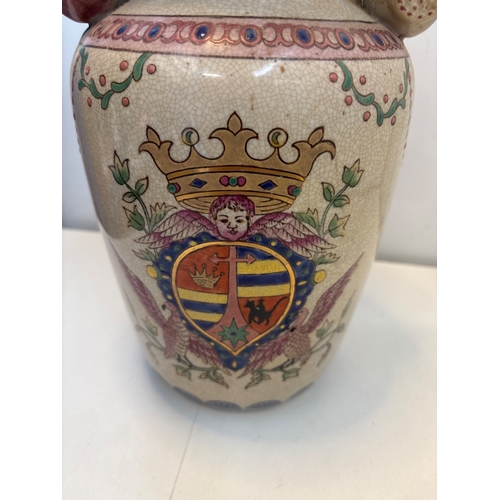 26 - Hand-painted ceramic vase featuring a crest design with a crown, angel motif, and floral accents not... 