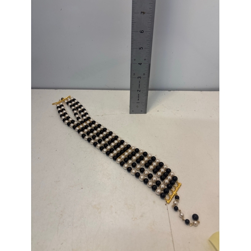 Braclet features multiple strands of alternating black and white beads ...