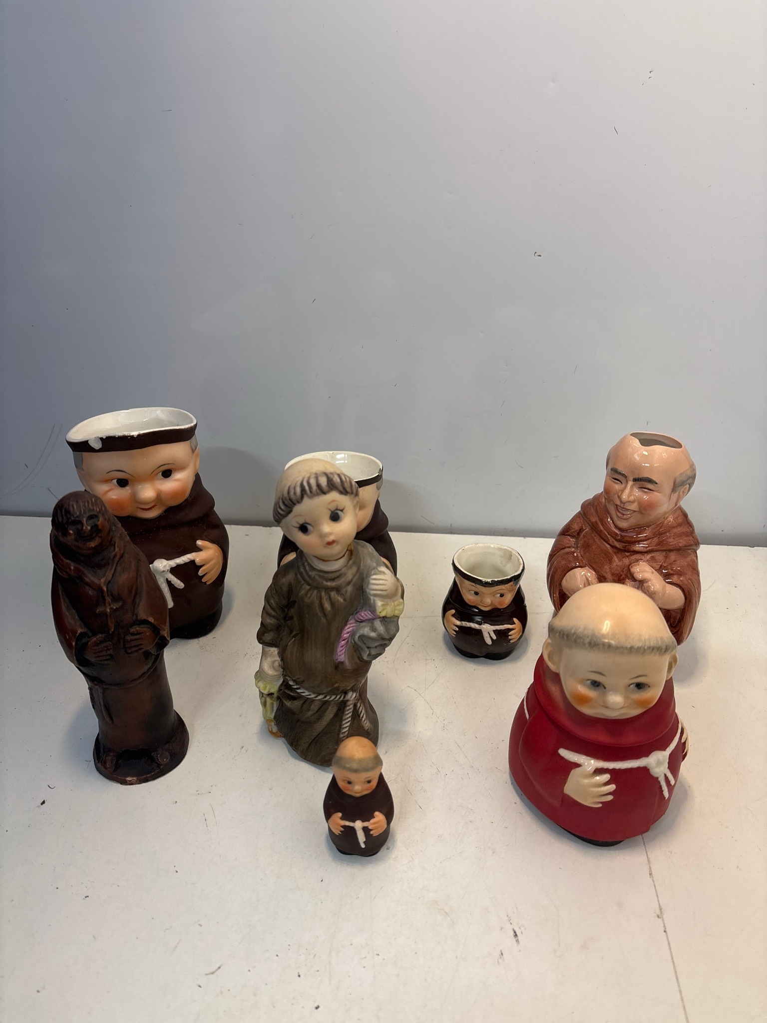 8 assorted ceramic figurines depicting monks and nuns. Various sizes ...