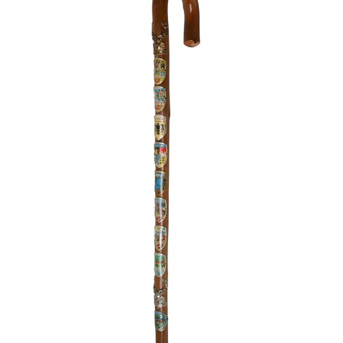 42 - Five Walking Canes - 2 with numerous badges attached, 1 with a horn handle and 2 with carved heads.