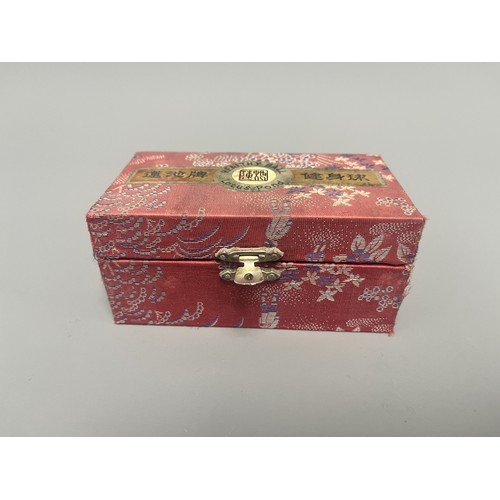 9 - A Pair of Lotus Pond Healthy Baoding Balls decorated with gold motifs, stored in a red fabric box la... 