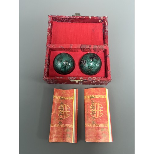 9 - A Pair of Lotus Pond Healthy Baoding Balls decorated with gold motifs, stored in a red fabric box la... 