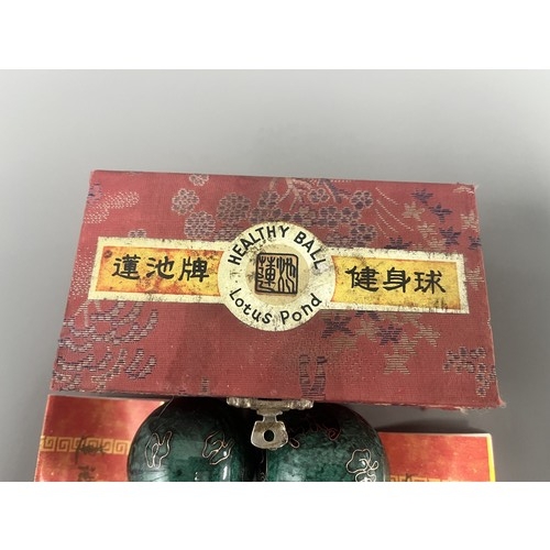 9 - A Pair of Lotus Pond Healthy Baoding Balls decorated with gold motifs, stored in a red fabric box la... 