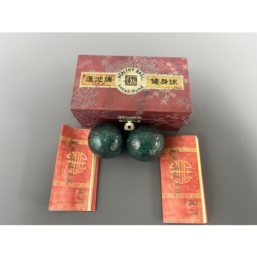 9 - A Pair of Lotus Pond Healthy Baoding Balls decorated with gold motifs, stored in a red fabric box la... 