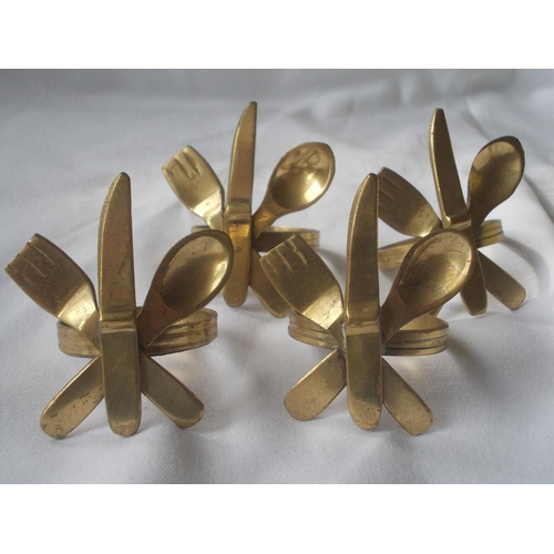 448 - A set of stylish vintage brass napkin rings in knife, fork and spoon design.