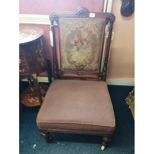 95 - An antique tapestry back nursing chair with carved wooden frame.