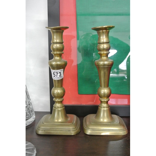 573 - A pair of antique brass candlesticks.