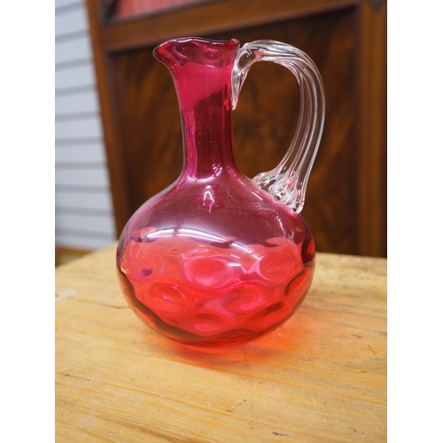 412 - An antique ruby glass jug with celery handle.