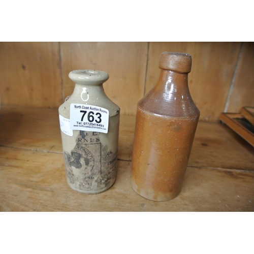 763 - A pair of stoneware bottles. One with part label