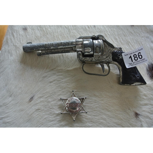 186 - A vintage Lone Star revolver along with a vintage toy badge reading, 'Sheriff - City of Tombstone.