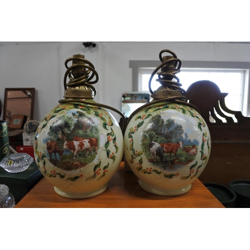 376 - A vintage pair of hand painted glass table lamps depicting scenes of cows.