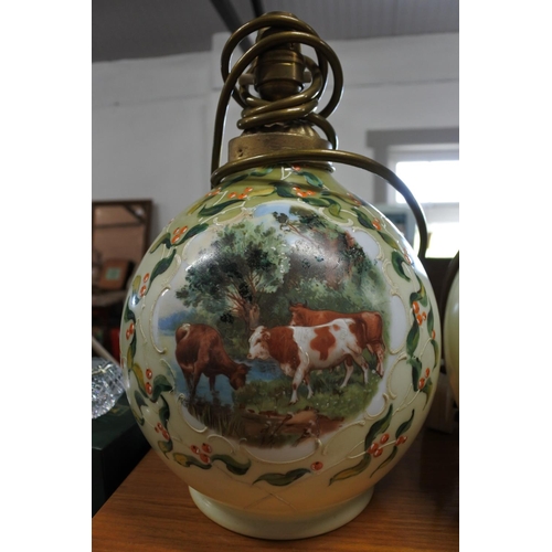 376 - A vintage pair of hand painted glass table lamps depicting scenes of cows.