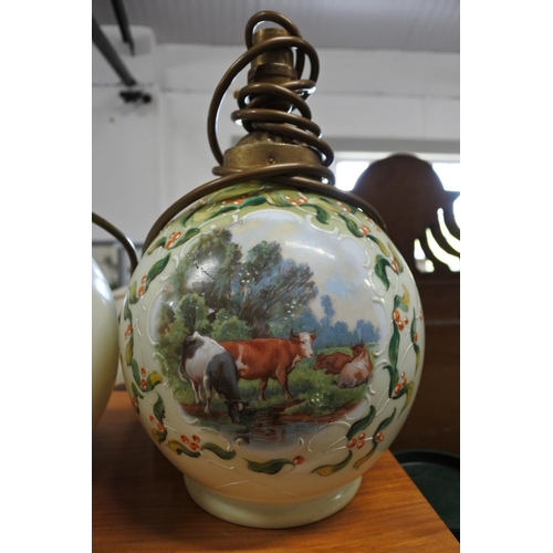 376 - A vintage pair of hand painted glass table lamps depicting scenes of cows.