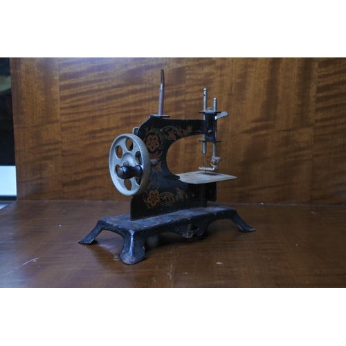 132 - A small tin plate model sewing machine.