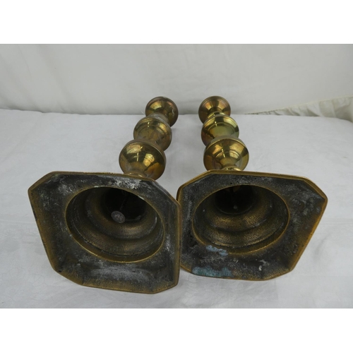 79 - A pair of antique brass candlesticks.