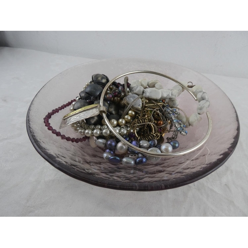 110 - An assortment of various costume jewellery in studio glass dish.