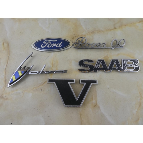 165 - An assorted lot of car badges to include Ford, Saab, Rover 90 and more.