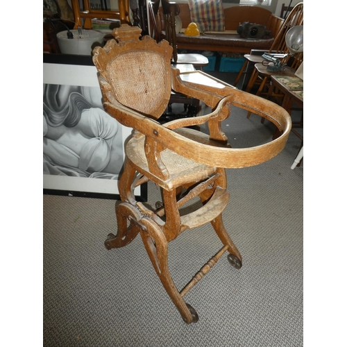 481 - A stunning antique oak high chair on cast iron rollers.