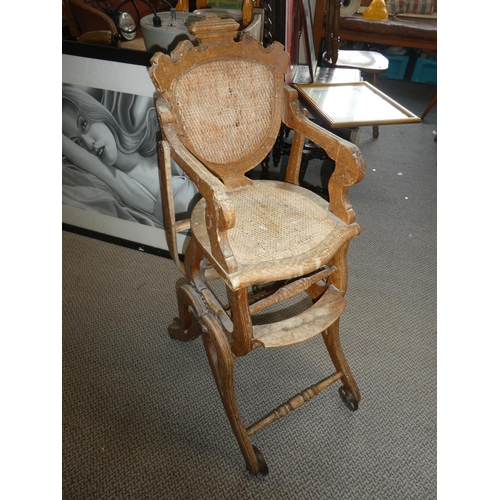 481 - A stunning antique oak high chair on cast iron rollers.