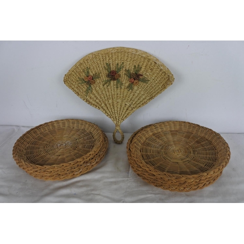 520 - A set of eight wicker plates and a decorative wicker fan.