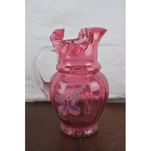 65 - A large antique ruby glass jug with hand painted floral detail (a/f).