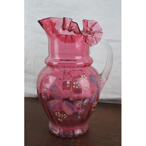 65 - A large antique ruby glass jug with hand painted floral detail (a/f).