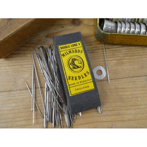 152 - An assortment of vintage thimbles and a vintage cardboard box containing sewing needles and more.