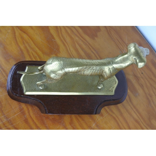 354 - A brass ornament of a dog mounted on a plinth, measuring 16cm tall.