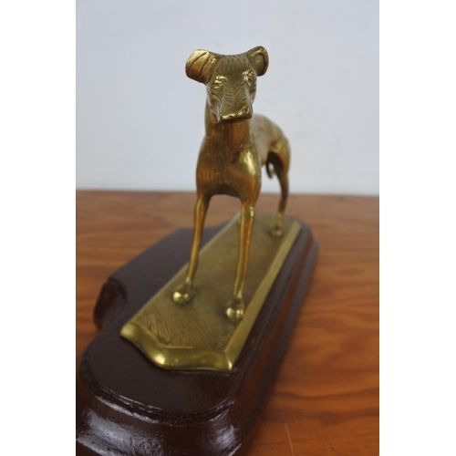 354 - A brass ornament of a dog mounted on a plinth, measuring 16cm tall.