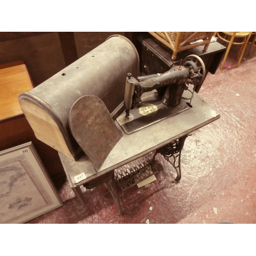 447 - An antique Singer sewing machine on cast iron base and original wooden cover.