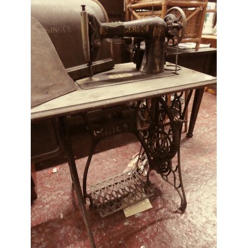 447 - An antique Singer sewing machine on cast iron base and original wooden cover.