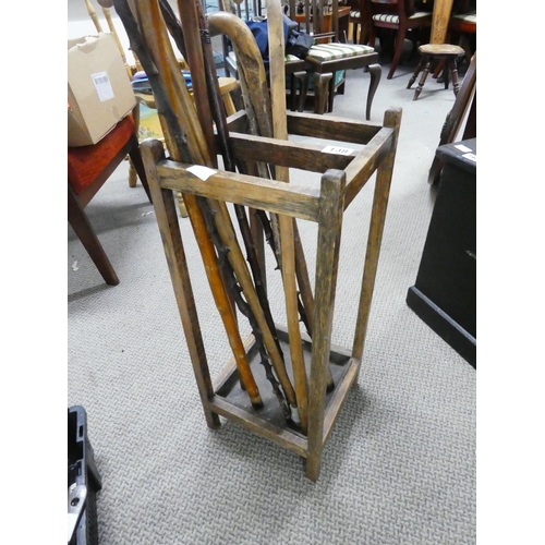 138 - An antique oak stick stand and a collection of walking sticks.