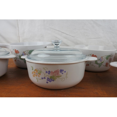 423 - Two Corning, France lidded casserole dishes, and a set of three saucepans.