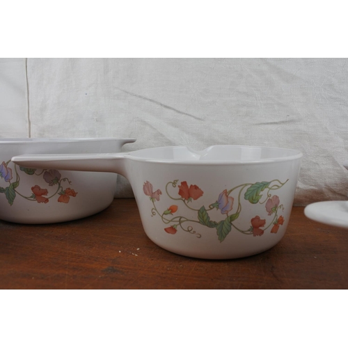 423 - Two Corning, France lidded casserole dishes, and a set of three saucepans.