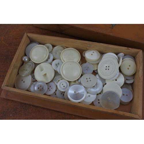 562 - A decorative pokerwork box with a collection of old white buttons.